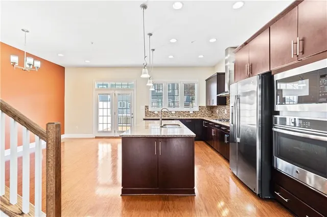 a kitchen with stainless steel appliances granite countertop a refrigerator a oven and a stove with wooden floor