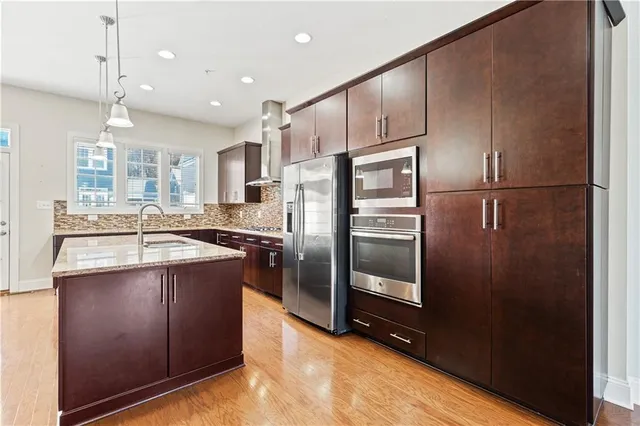 a kitchen with kitchen island a counter top space a sink stainless steel appliances and cabinets