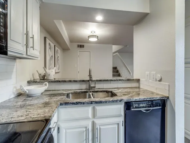 a kitchen with granite countertop a sink and a white cabinets