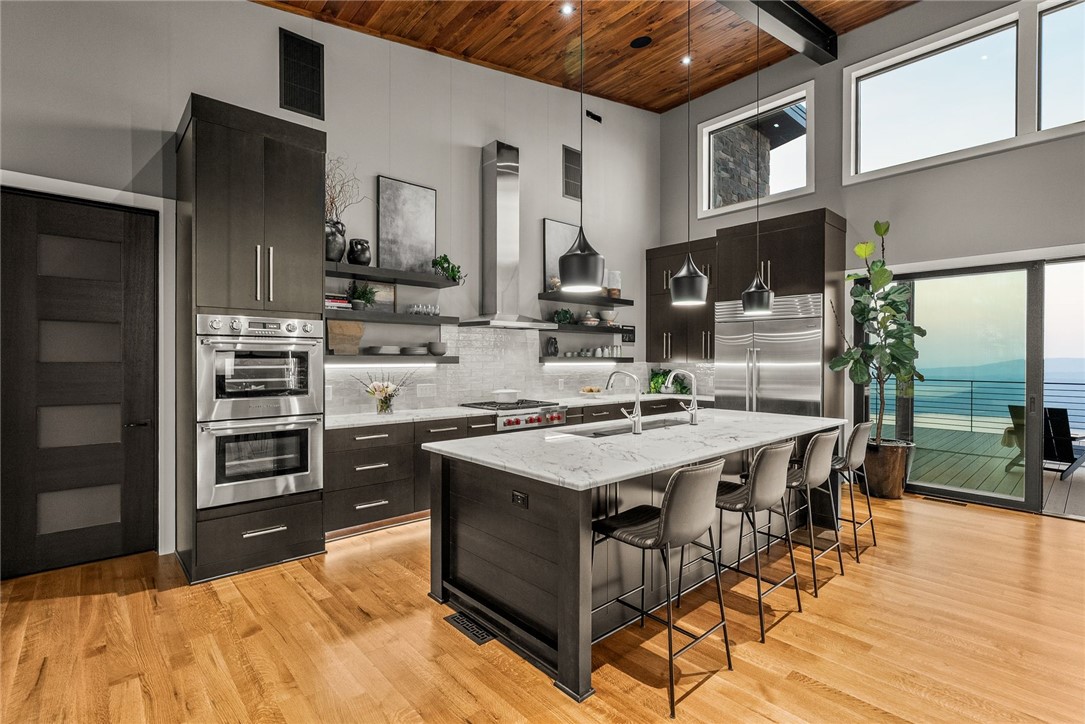 2623 Alum Cave Road Bee Branch, AR 72013 - Photo 19 of 60 Modern kitchen featuring a large central island with seating, stainless steel appliances, dark wood-finish cabinetry, wood-finish flooring, and a vaulted ceiling with wood paneling