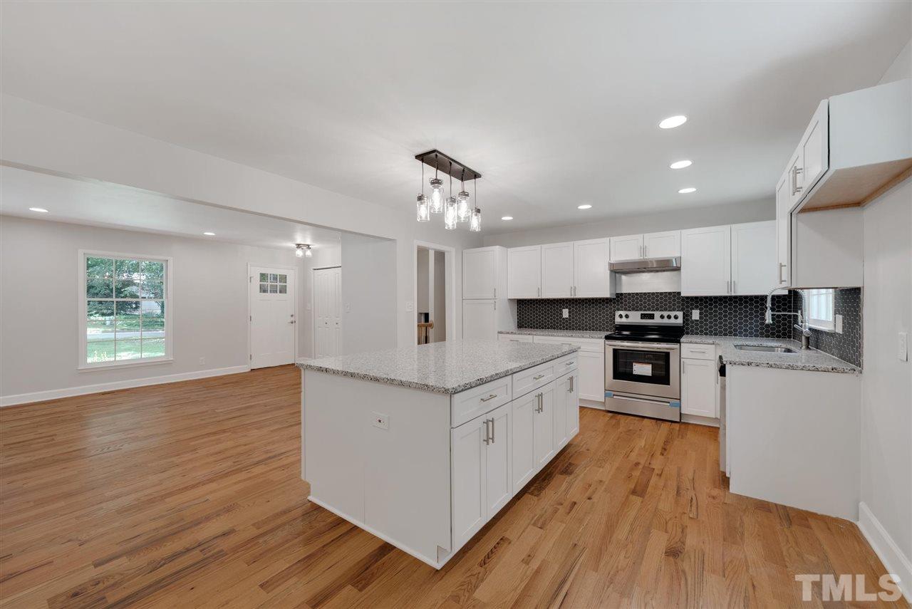 7409 Fiesta Way Raleigh, NC 27615 - Photo 6 of 30 a kitchen with stainless steel appliances granite countertop a stove top oven a sink dishwasher and a refrigerator with wooden floor