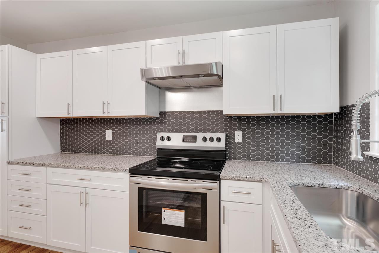 7409 Fiesta Way Raleigh, NC 27615 - Photo 7 of 30 a kitchen with granite countertop white cabinets and a stove