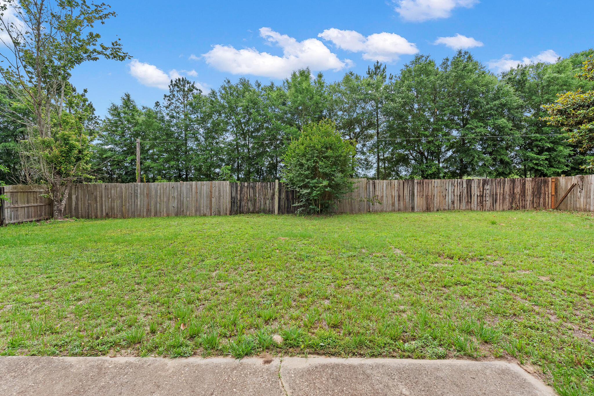 2246 Titanium Drive Crestview, FL 32536 - Photo 27 of 28 a view of a yard with a fence and trees