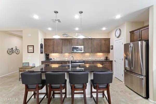 a kitchen with granite countertop a table chairs stove and refrigerator