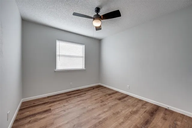 an empty room with a window and a ceiling fan
