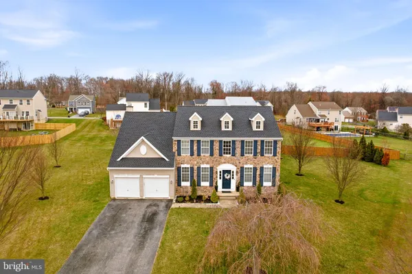 a view of a house with a big yard with plants and large trees