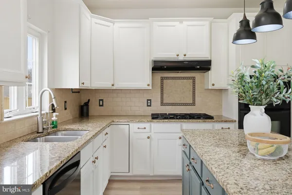a kitchen with granite countertop white cabinets and a sink