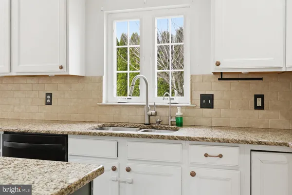 a kitchen with granite countertop a sink a stove and cabinets