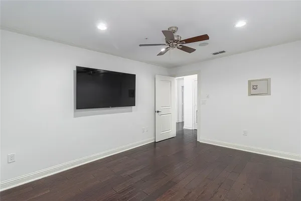 an empty room with wooden floor fan and windows