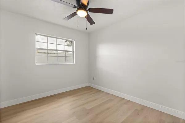 an empty room with a window and a fan