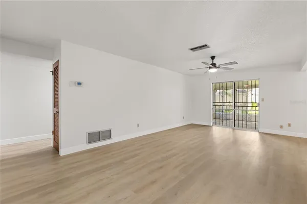 a view of an empty room with a window and wooden floor