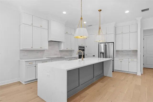 a kitchen with stainless steel appliances granite countertop a sink a refrigerator and a stove