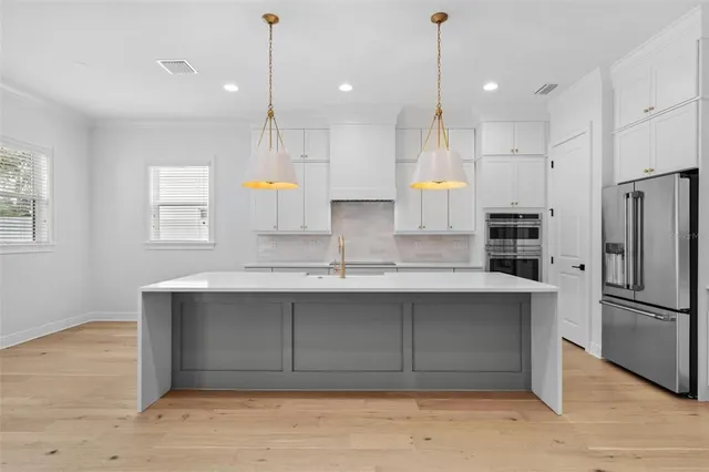 a view of an empty room with wooden floor and a ceiling fan