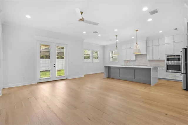 a view of an empty room with kitchen and window