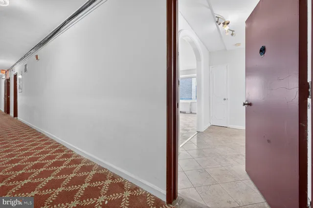 a view of a hallway with wooden floor and a bathroom