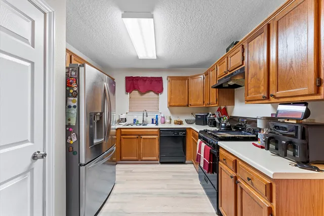 a kitchen with stainless steel appliances granite countertop a refrigerator and a stove top oven