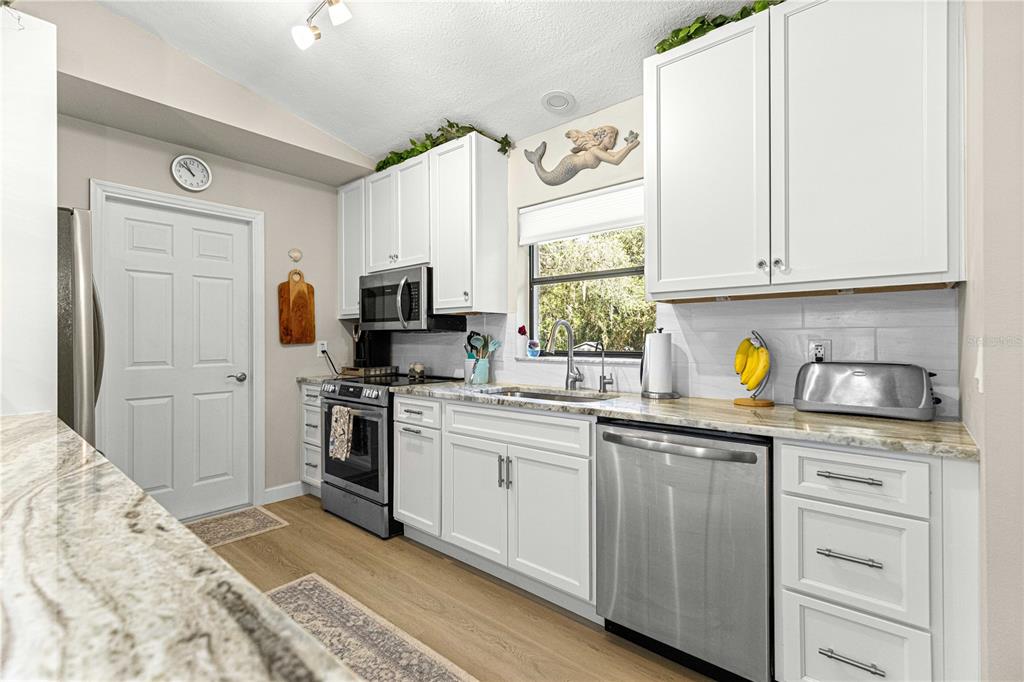 1155 East Bismark Street Hernando, FL 34442 - Photo 6 of 52 a kitchen with kitchen island granite countertop a sink cabinets stainless steel appliances and a window