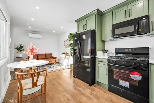 a kitchen with stainless steel appliances kitchen island granite countertop a refrigerator oven a stove top oven and a dining table with wooden floor