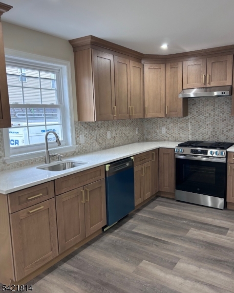 a kitchen with stainless steel appliances granite countertop a sink and cabinets with wooden floors