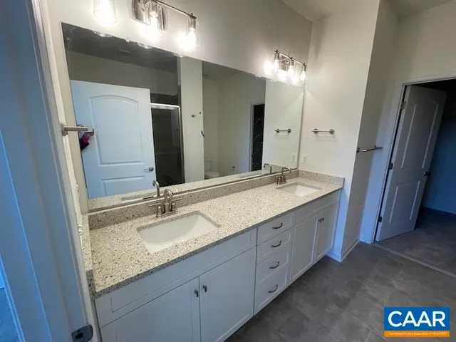 a bathroom with a granite countertop double vanity sink and a mirror