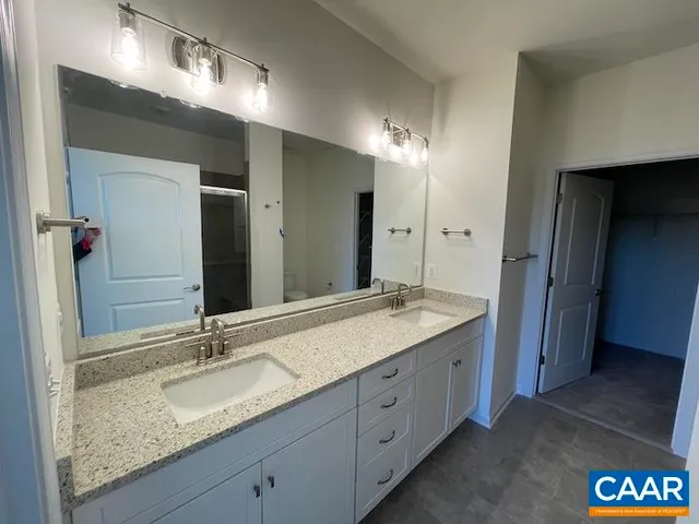 a bathroom with a granite countertop double vanity sink and a mirror