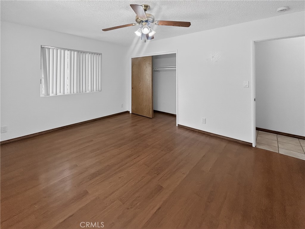 7451 Diamond Street Riverside, CA 92504 - Photo 20 of 31 an empty room with wooden floor chandelier fan and windows