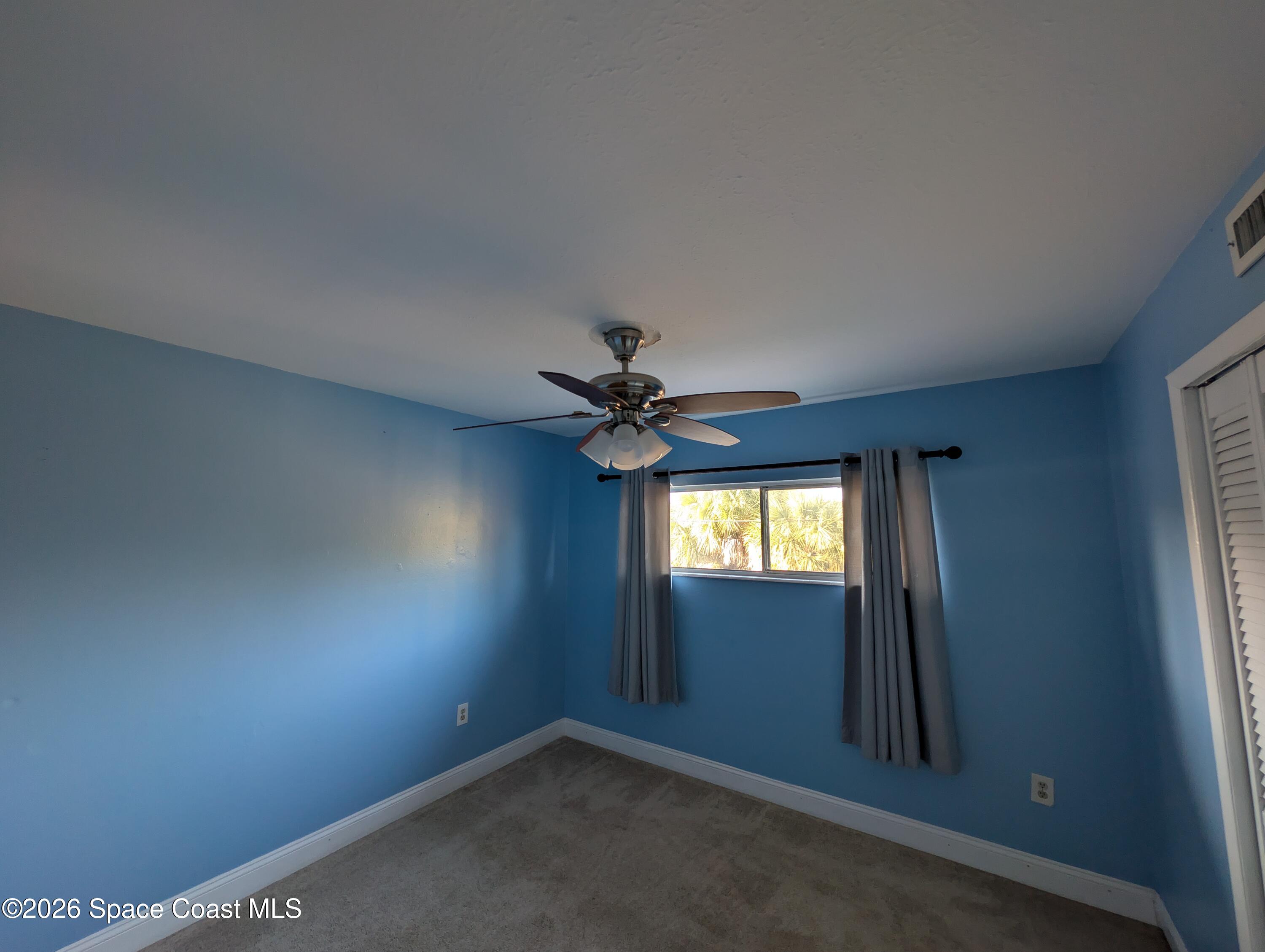 180 Minna Lane, Unit 407 Merritt Island, FL 32953 - Photo 5 of 8 an empty room with windows and fan