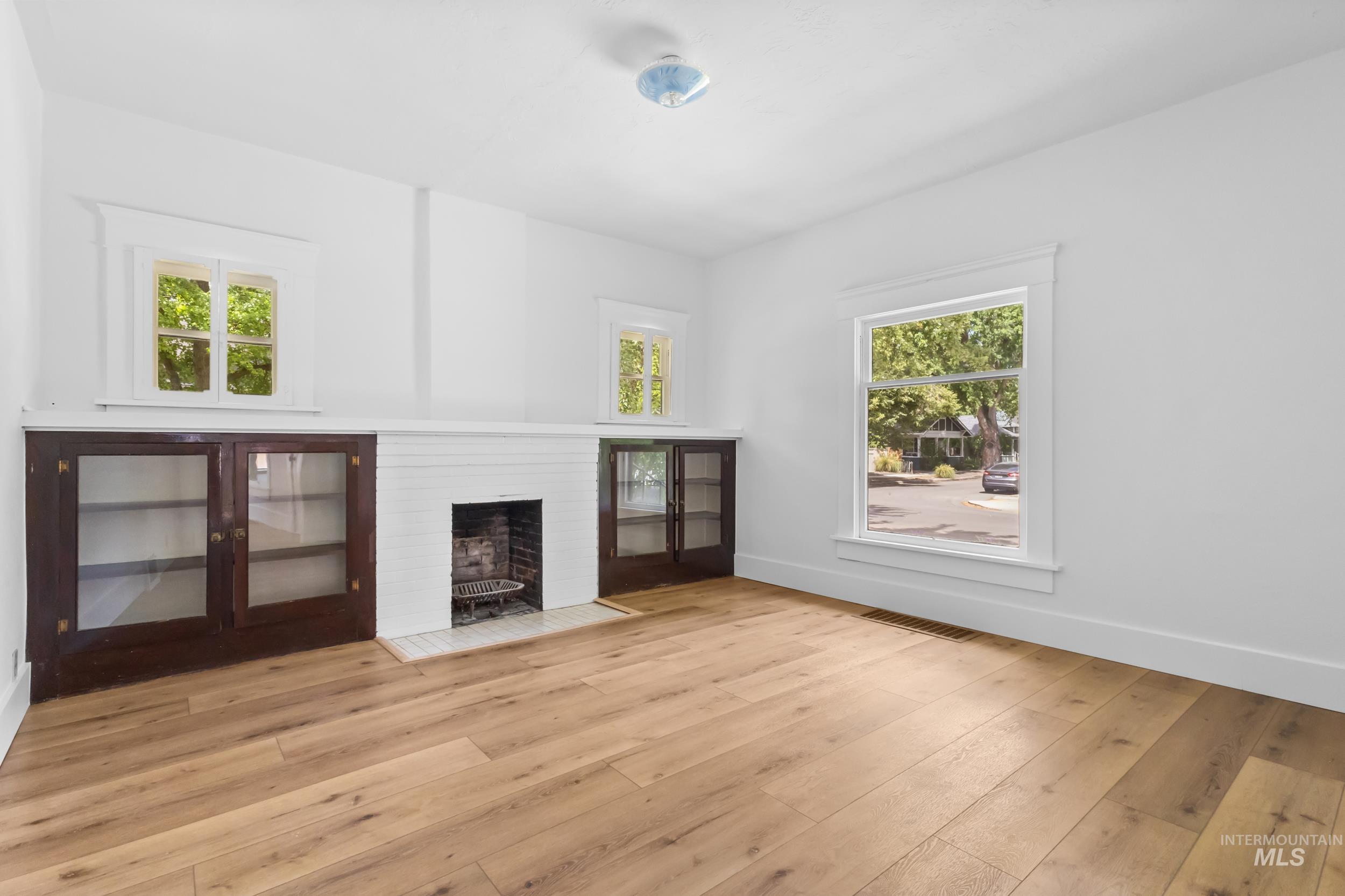 2119 West Brumback Street Boise, ID 83702 - Photo 9 of 30 Bright interior space featuring wood-finish flooring, white walls, and a fireplace with a white brick surround and hearth
