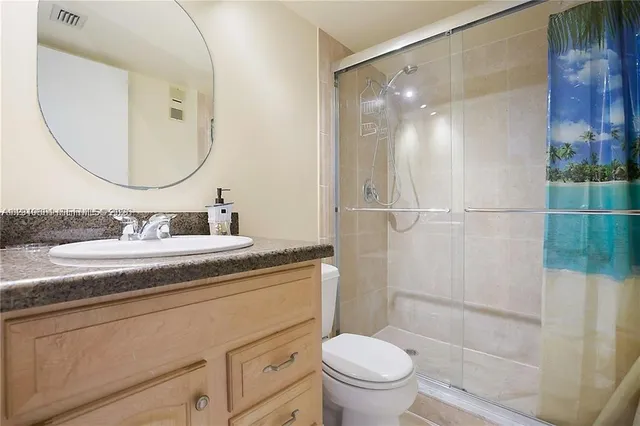 a bathroom with a granite countertop sink toilet and shower