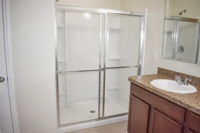 a bathroom with a granite countertop shower sink and mirror