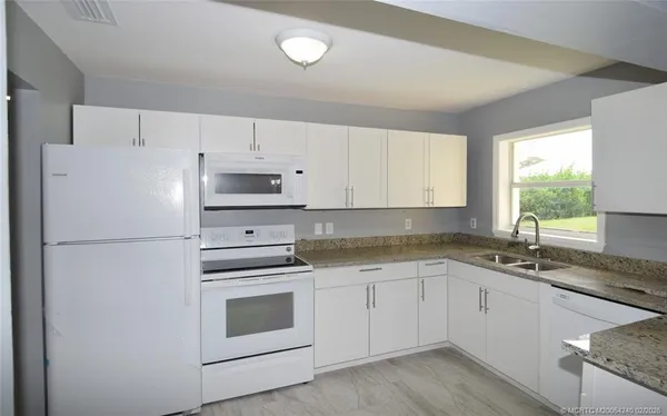 a white kitchen with granite countertop white cabinets and white appliances