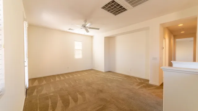 an empty room with windows and fan