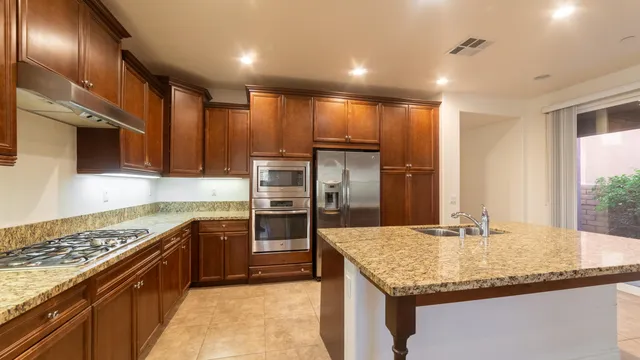 a kitchen with kitchen island granite countertop a sink refrigerator and cabinets