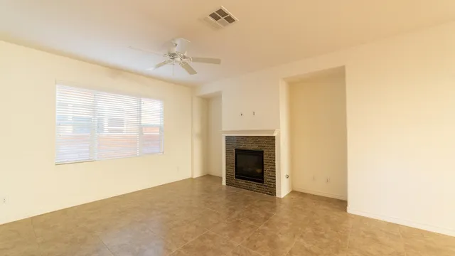 a view of a livingroom with a fireplace a ceiling fan and wooden floor