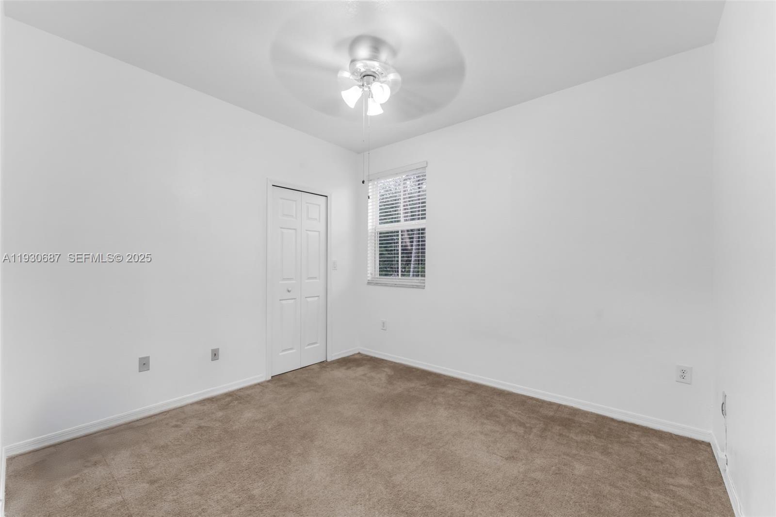 13820 Southwest 275th Street Homestead, FL 33032 - Photo 14 of 36 an empty room with a chandelier fan and windows