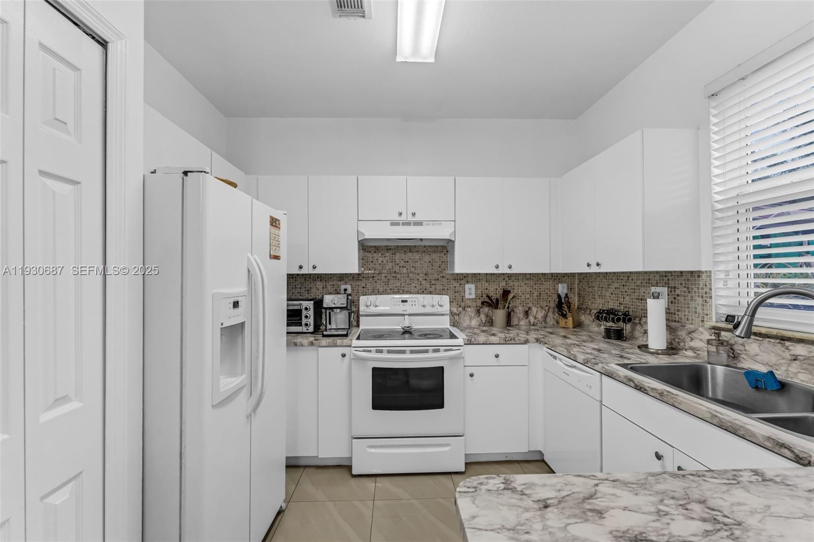 13820 Southwest 275th Street Homestead, FL 33032 - Photo 9 of 36 a kitchen with white cabinets and white appliances