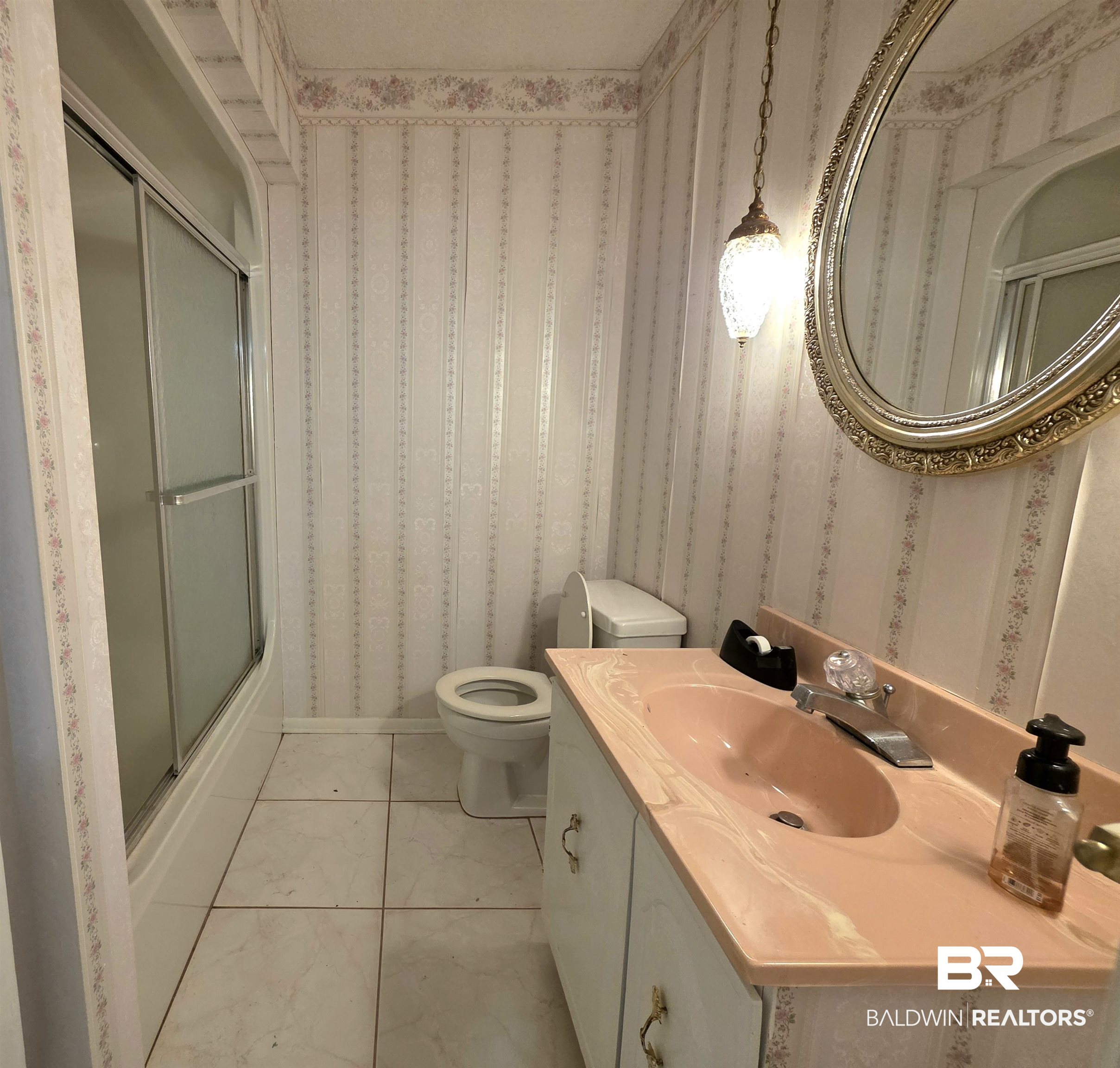 558 Stanton Road Atmore, AL 36502 - Photo 12 of 29 Bathroom featuring a shower with sliding glass doors, a single vanity with a peach-toned countertop and integrated sink, a toilet, and patterned wallpaper