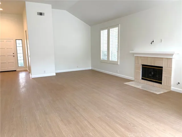 an empty room with windows and fireplace