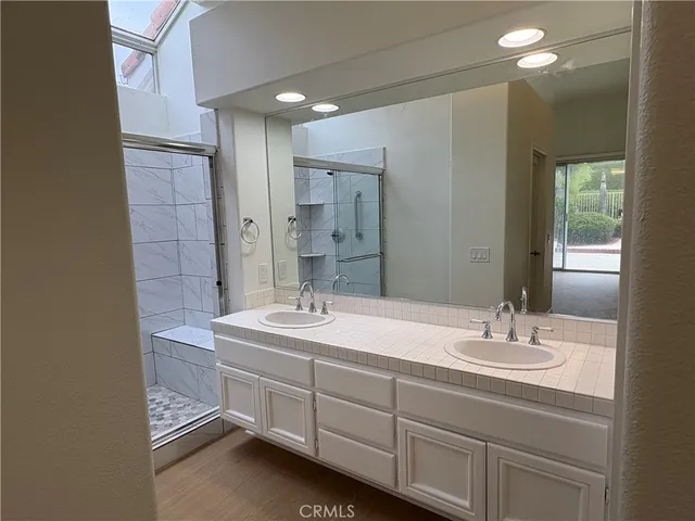 a bathroom with a double vanity sink a mirror and a shower