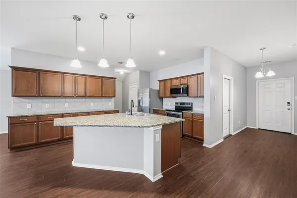 a view of a kitchen counter top space stainless steel appliances and wooden floor