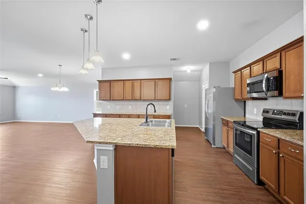 a large kitchen with stainless steel appliances granite countertop a sink a stove and a wooden floors