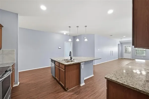 a kitchen with stainless steel appliances granite countertop a sink a stove and a wooden floors