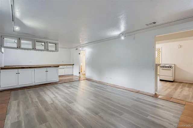 a view of a livingroom with wooden floor and a kitchen space