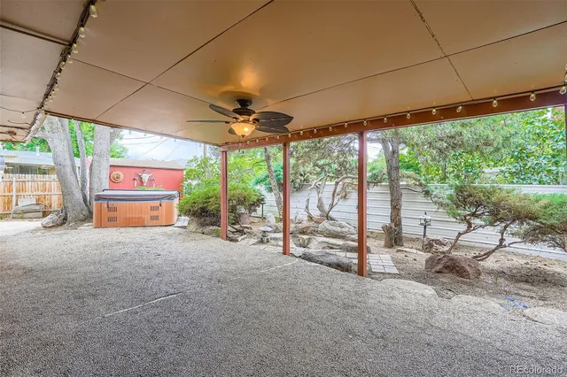 a view of a backyard with large trees and wooden fence