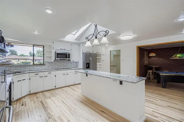 a large kitchen with granite countertop a large counter top space appliances and cabinets