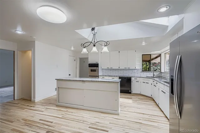 a large kitchen with cabinets wooden floor and stainless steel appliances