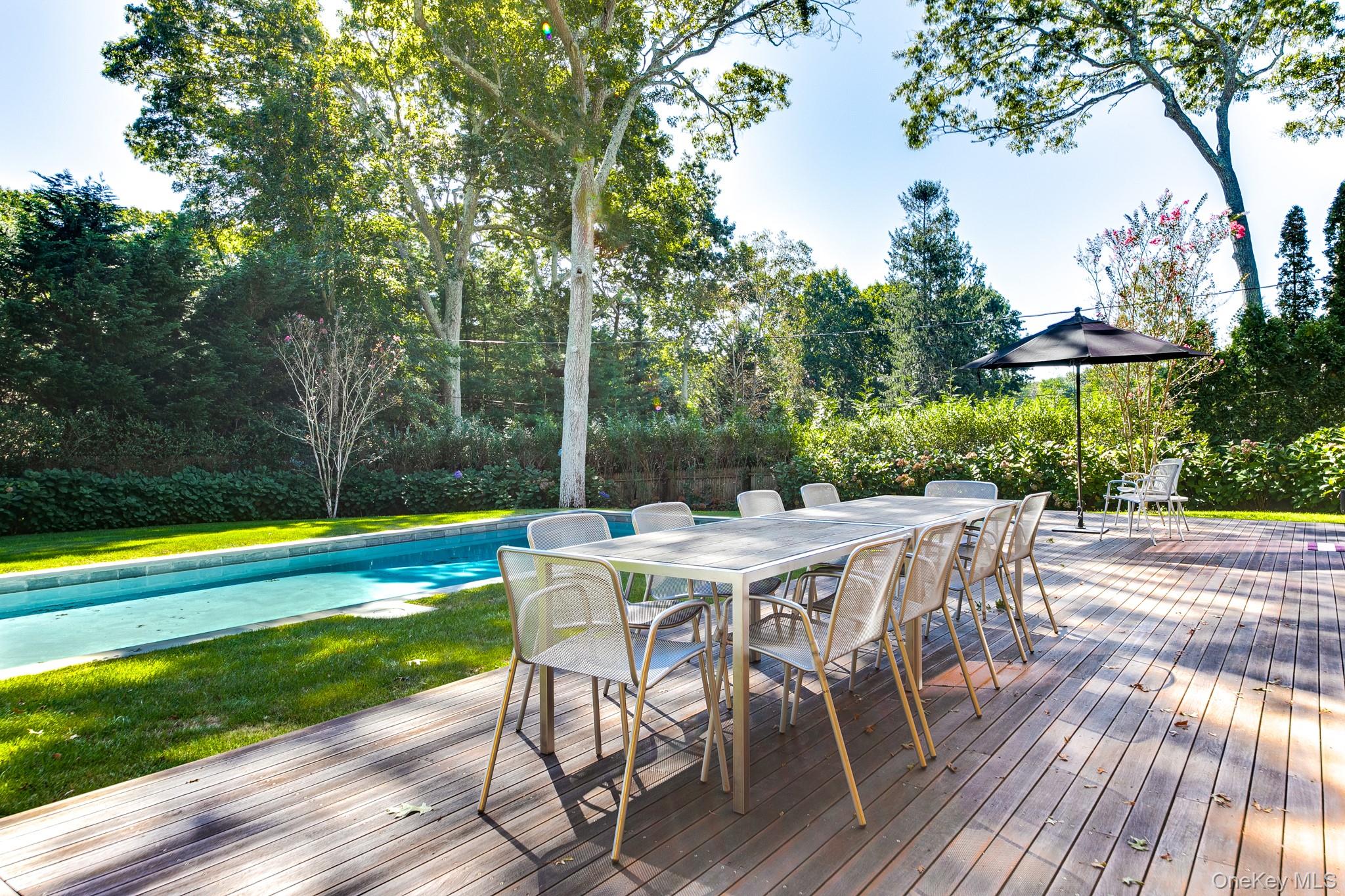 70 Cove Hollow Road East Hampton, NY 11937 - Photo 6 of 21 Wooden terrace with an outdoor pool, outdoor dining area, a yard, and view of wooded area