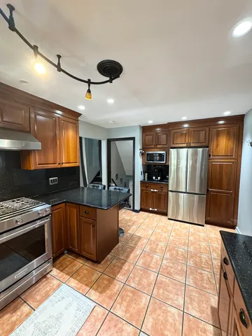 a kitchen with stainless steel appliances kitchen island granite countertop a refrigerator and a stove top oven