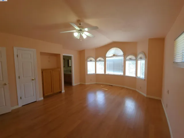 a view of an empty room with a window and wooden floor