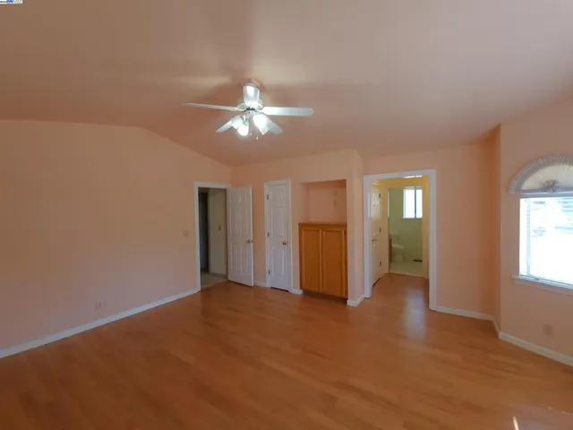 an empty room with chandelier fan and windows